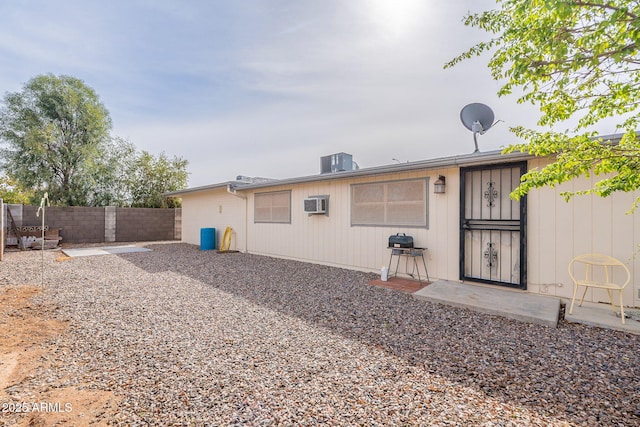 rear view of house featuring cooling unit, a wall mounted air conditioner, and fence