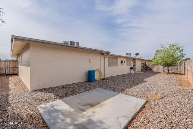 back of property featuring a patio, a fenced backyard, brick siding, and central AC