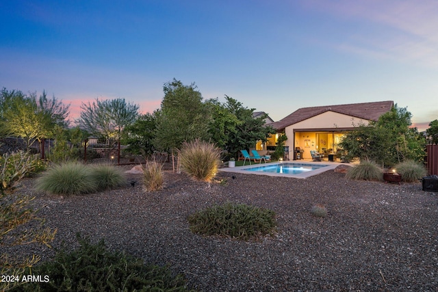 yard at dusk featuring a patio and a fenced in pool