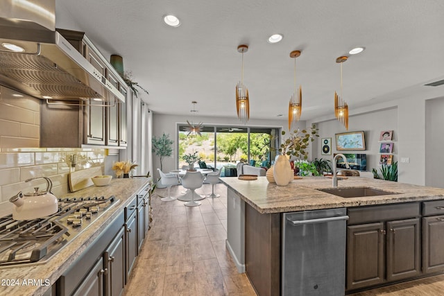 kitchen featuring stainless steel gas stovetop, light hardwood / wood-style floors, sink, and decorative light fixtures