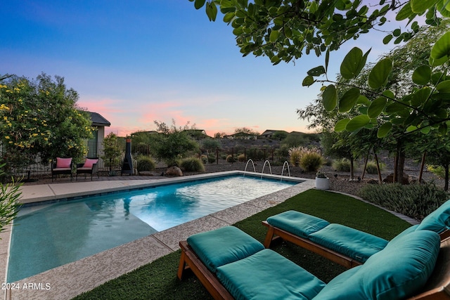 pool at dusk with a patio area