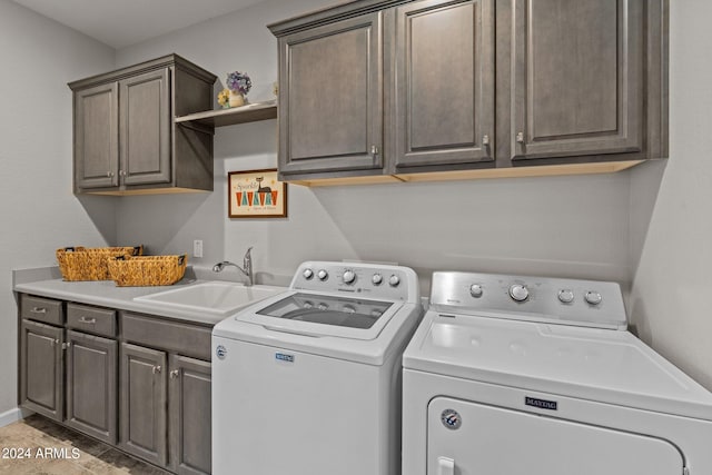 laundry area with cabinets, washer and clothes dryer, and sink