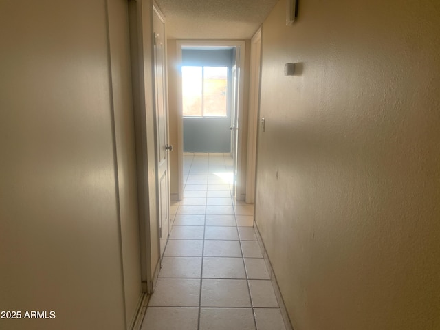 hall with light tile patterned floors and a textured ceiling