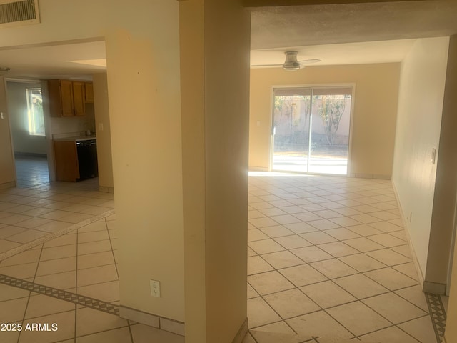 hall featuring light tile patterned flooring, a healthy amount of sunlight, visible vents, and baseboards