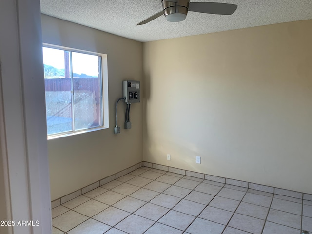 empty room with light tile patterned flooring, a ceiling fan, and a textured ceiling