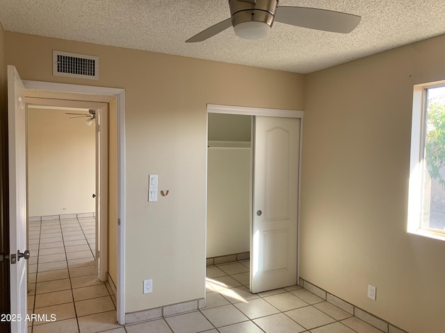 unfurnished bedroom with visible vents, ceiling fan, light tile patterned flooring, a closet, and a textured ceiling