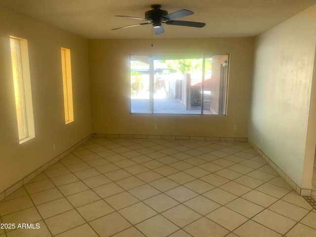 empty room with light tile patterned floors and a ceiling fan