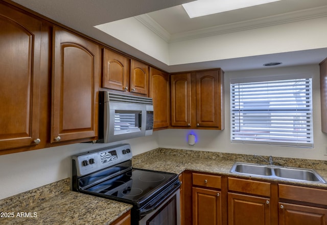 3330 W Danbury Dr Unit E203, Phoenix, AZ 85053 - kitchen with electric range, stainless steel microwave, crown molding, brown cabinetry, and light countertops