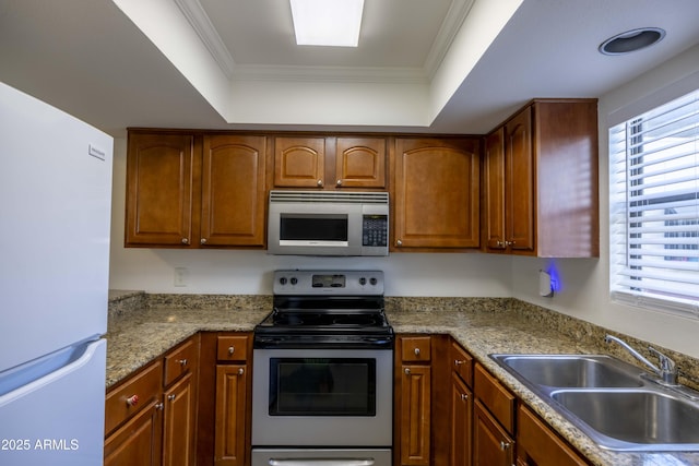 3330 W Danbury Dr Unit E203, Phoenix, AZ 85053 - kitchen featuring appliances with stainless steel finishes, brown cabinets, a raised ceiling, and ornamental molding
