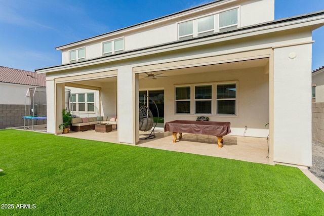 rear view of property featuring a lawn, outdoor lounge area, a patio, and a trampoline