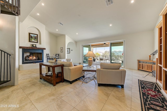 living room with high vaulted ceiling, arched walkways, visible vents, and a lit fireplace