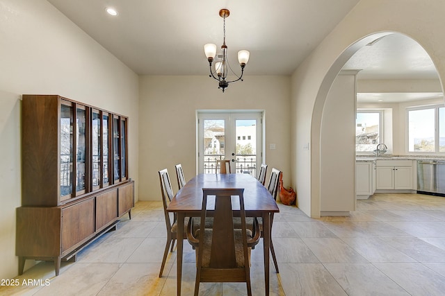 dining space with arched walkways, a notable chandelier, recessed lighting, and french doors