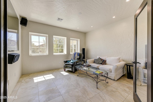 living area with light tile patterned floors, recessed lighting, visible vents, and a textured ceiling