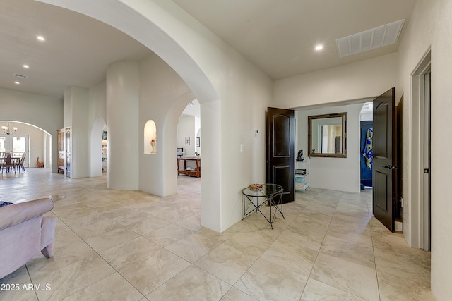 hall with recessed lighting, visible vents, a chandelier, and arched walkways