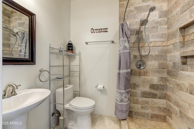 bathroom with a sink, toilet, and tiled shower