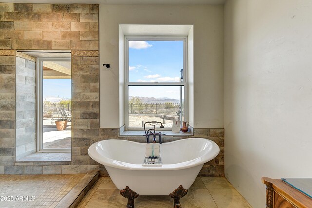 bathroom featuring a freestanding bath, tile walls, and wainscoting