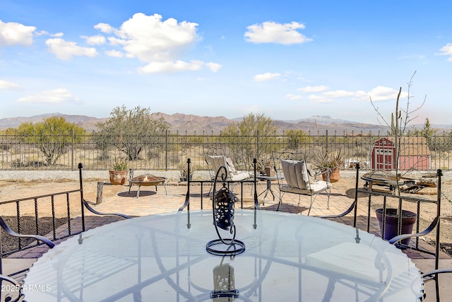 view of patio / terrace featuring a mountain view, a fire pit, and fence