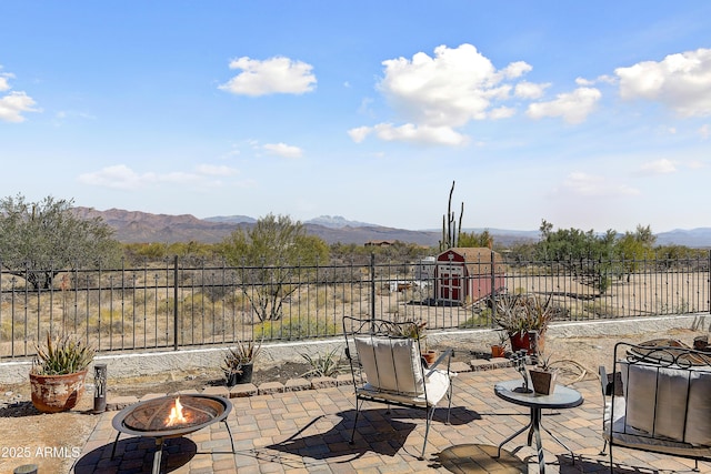 view of patio with a mountain view, an outdoor fire pit, and fence