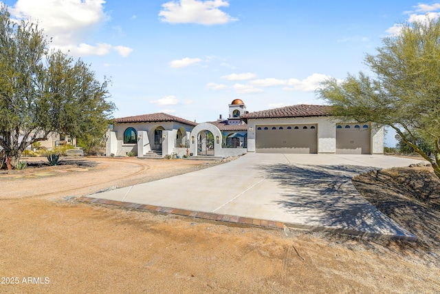 mediterranean / spanish home featuring stucco siding, a garage, driveway, and a tile roof