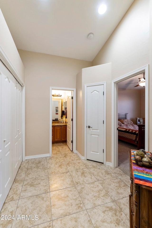 hall with lofted ceiling and light tile patterned flooring