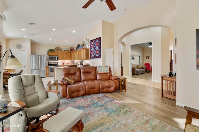 living room with ceiling fan, light hardwood / wood-style floors, and vaulted ceiling