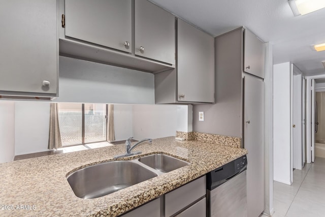 kitchen with light stone countertops, sink, light tile patterned floors, and dishwasher