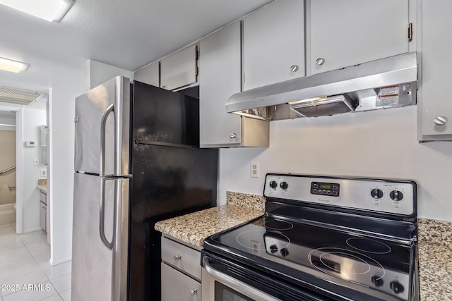 kitchen with light stone countertops, a textured ceiling, appliances with stainless steel finishes, and light tile patterned flooring