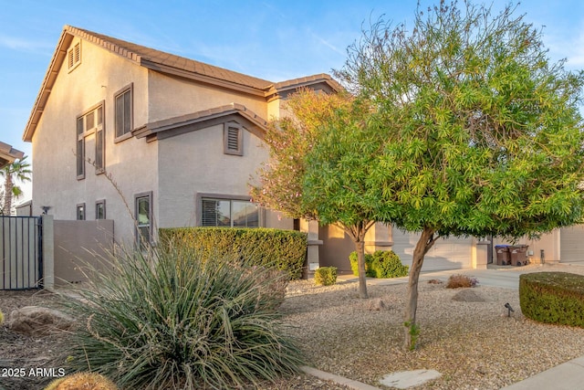 view of property exterior featuring a tiled roof, fence, driveway, and stucco siding