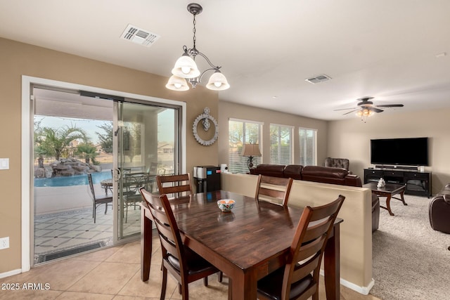 dining space with light tile patterned floors, visible vents, and ceiling fan with notable chandelier