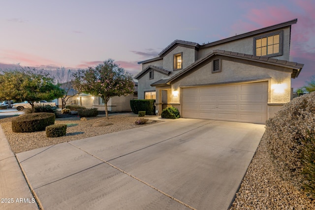 traditional-style house with a garage, concrete driveway, and stucco siding