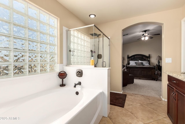 ensuite bathroom with a stall shower, a ceiling fan, connected bathroom, a garden tub, and tile patterned flooring