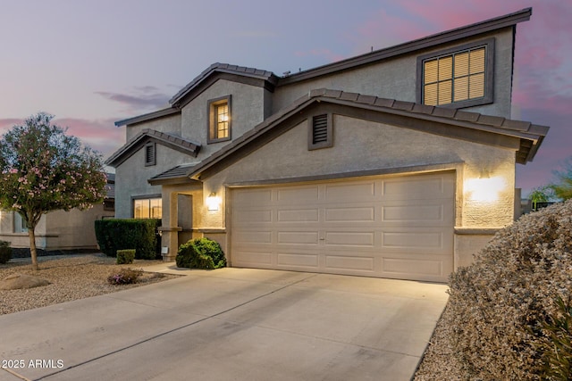 traditional home with a garage, driveway, a tiled roof, and stucco siding