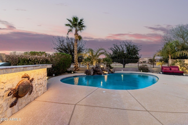 pool at dusk with a patio area, fence, and a fenced in pool