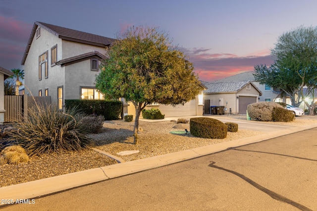 view of front of house featuring driveway, a garage, fence, an outdoor structure, and stucco siding