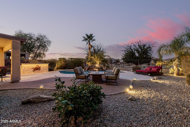 yard at dusk featuring a fire pit, a patio, fence, and a fenced in pool