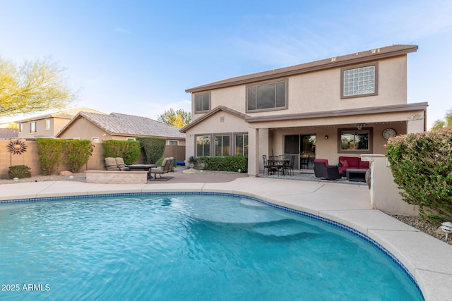 rear view of property featuring a fenced in pool, a patio, fence, and stucco siding