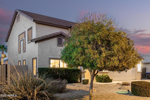 view of side of property with fence, an attached garage, and stucco siding