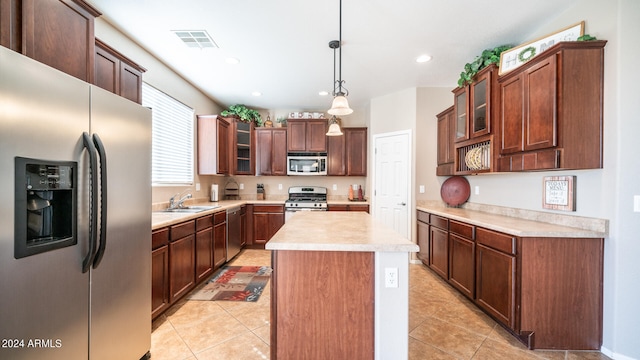 kitchen featuring sink, a kitchen island, hanging light fixtures, stainless steel appliances, and light tile patterned floors