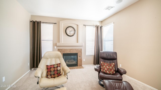 sitting room with a tiled fireplace and light colored carpet