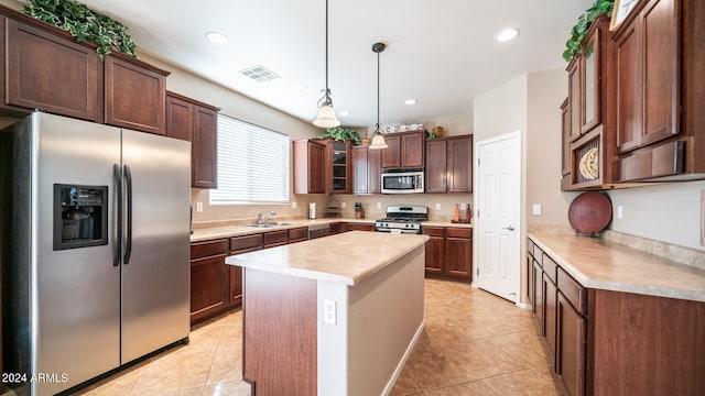 kitchen featuring appliances with stainless steel finishes, light tile patterned flooring, pendant lighting, and a kitchen island