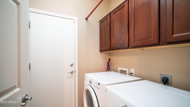 clothes washing area featuring independent washer and dryer and cabinets