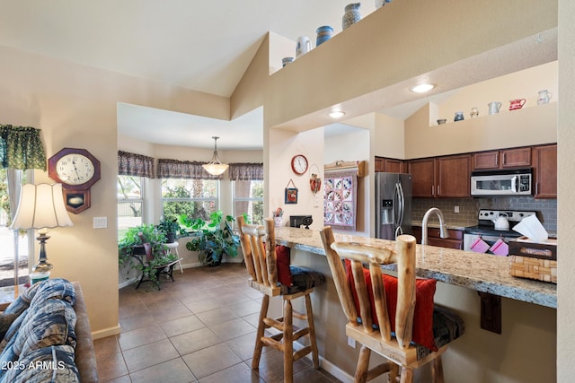 4002 N San Gabriel Cir, Mesa, AZ 85215 - kitchen featuring stainless steel appliances, tile patterned flooring, a breakfast bar area, decorative backsplash, and vaulted ceiling
