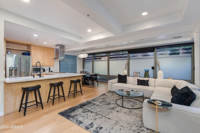 living room with a tray ceiling and light hardwood / wood-style floors