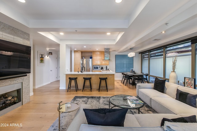 living room featuring light hardwood / wood-style flooring and a tray ceiling