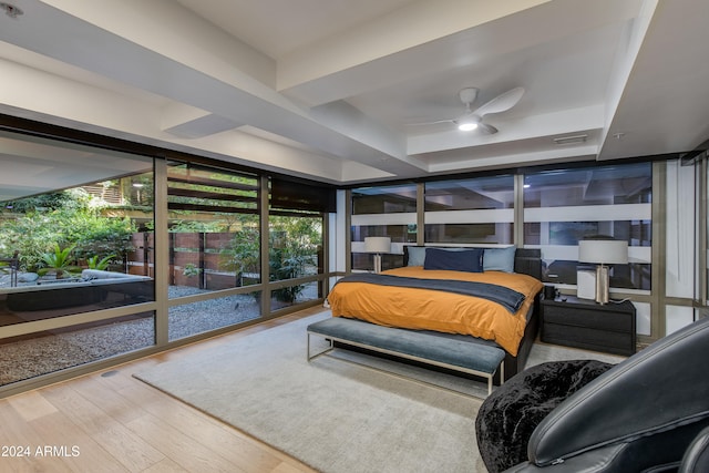 bedroom with ceiling fan, hardwood / wood-style flooring, a raised ceiling, and floor to ceiling windows