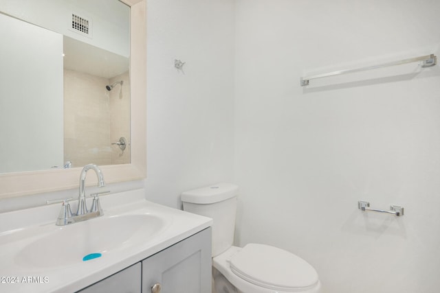 bathroom featuring vanity, toilet, and tiled shower