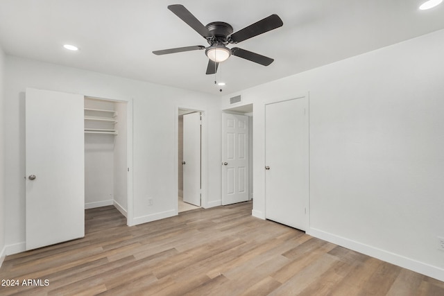 unfurnished bedroom featuring light hardwood / wood-style flooring, a walk in closet, and ceiling fan