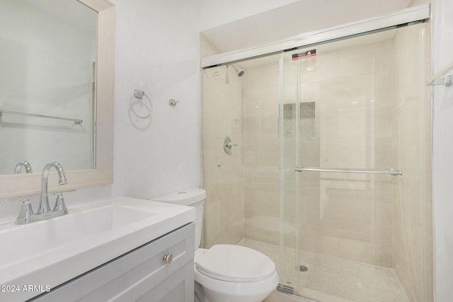 bathroom featuring a shower with door, toilet, and vanity