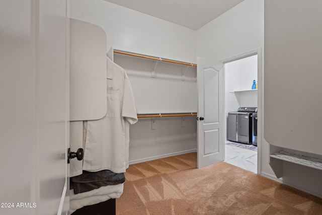 walk in closet featuring washer and clothes dryer and light colored carpet