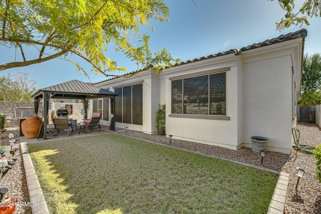 back of property with a gazebo, a patio, a lawn, and a sunroom